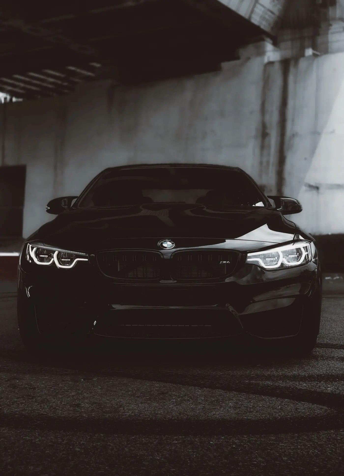 Schwarzer BMW M4 von vorne mit eingeschalteten Scheinwerfern